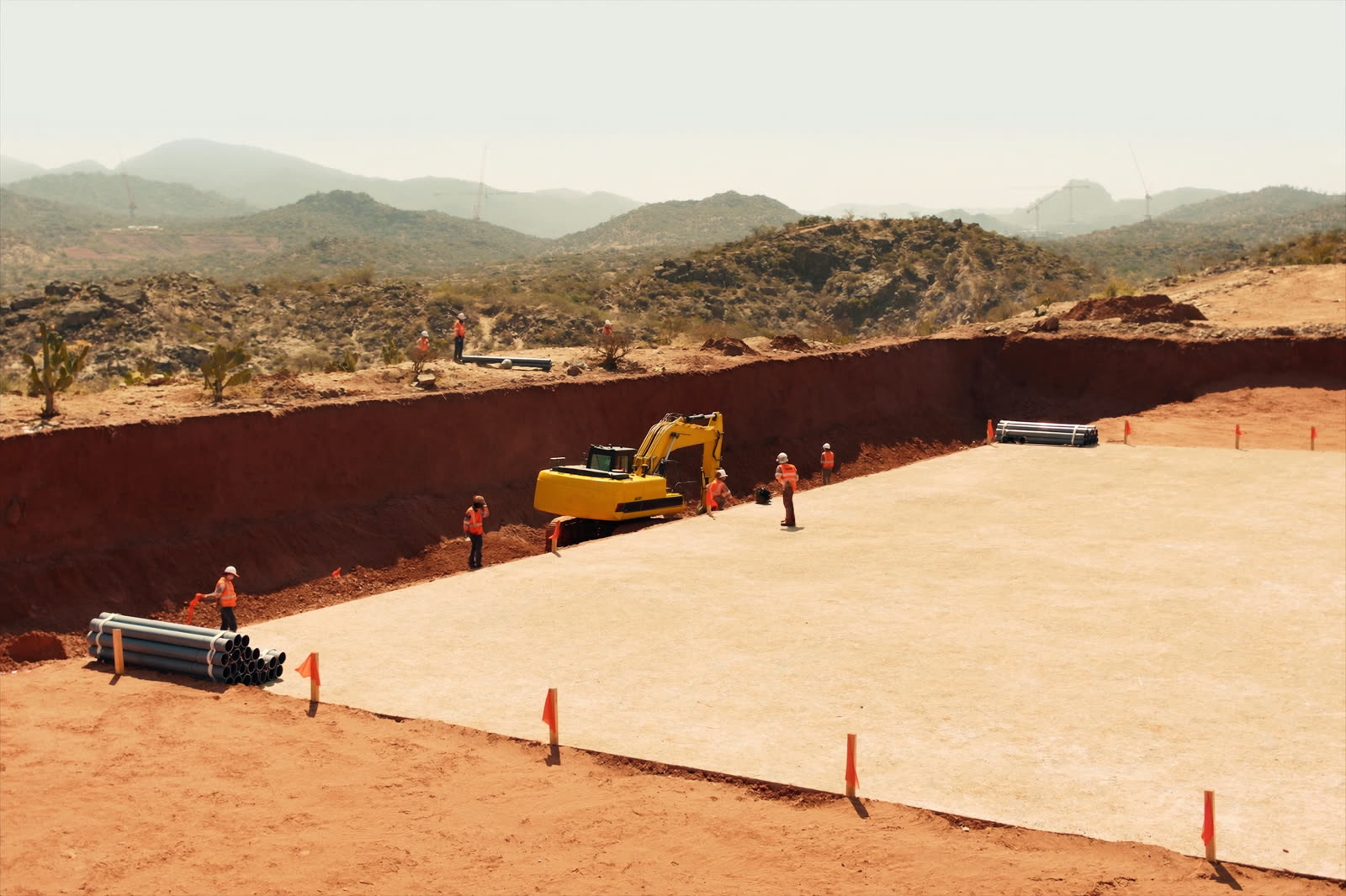 Excavadora ejecutando corte y movimiento de tierras en plataforma de urbanización